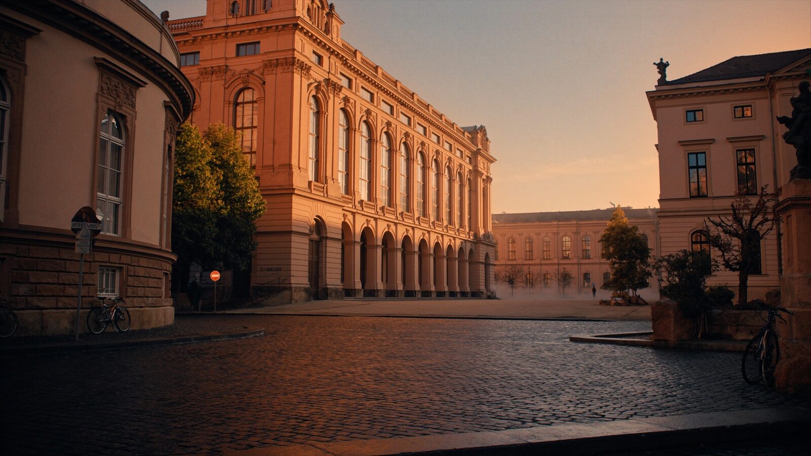Empty cobblestone square in a historic German university town at dawn with sandstone buildings and a few parked bicycles