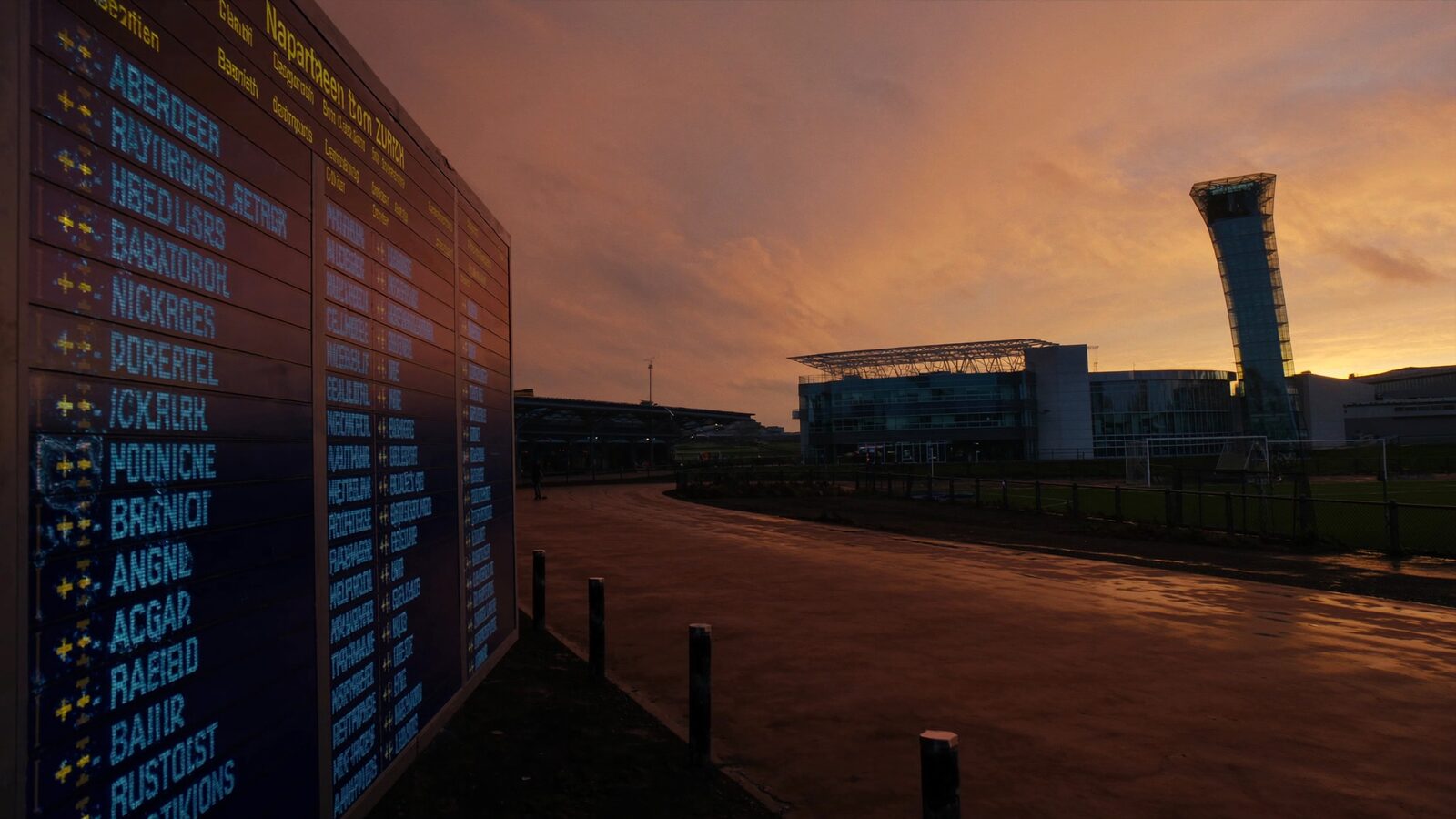 Empty university campus at dawn with modern research buildings and a distant airport tower under golden light