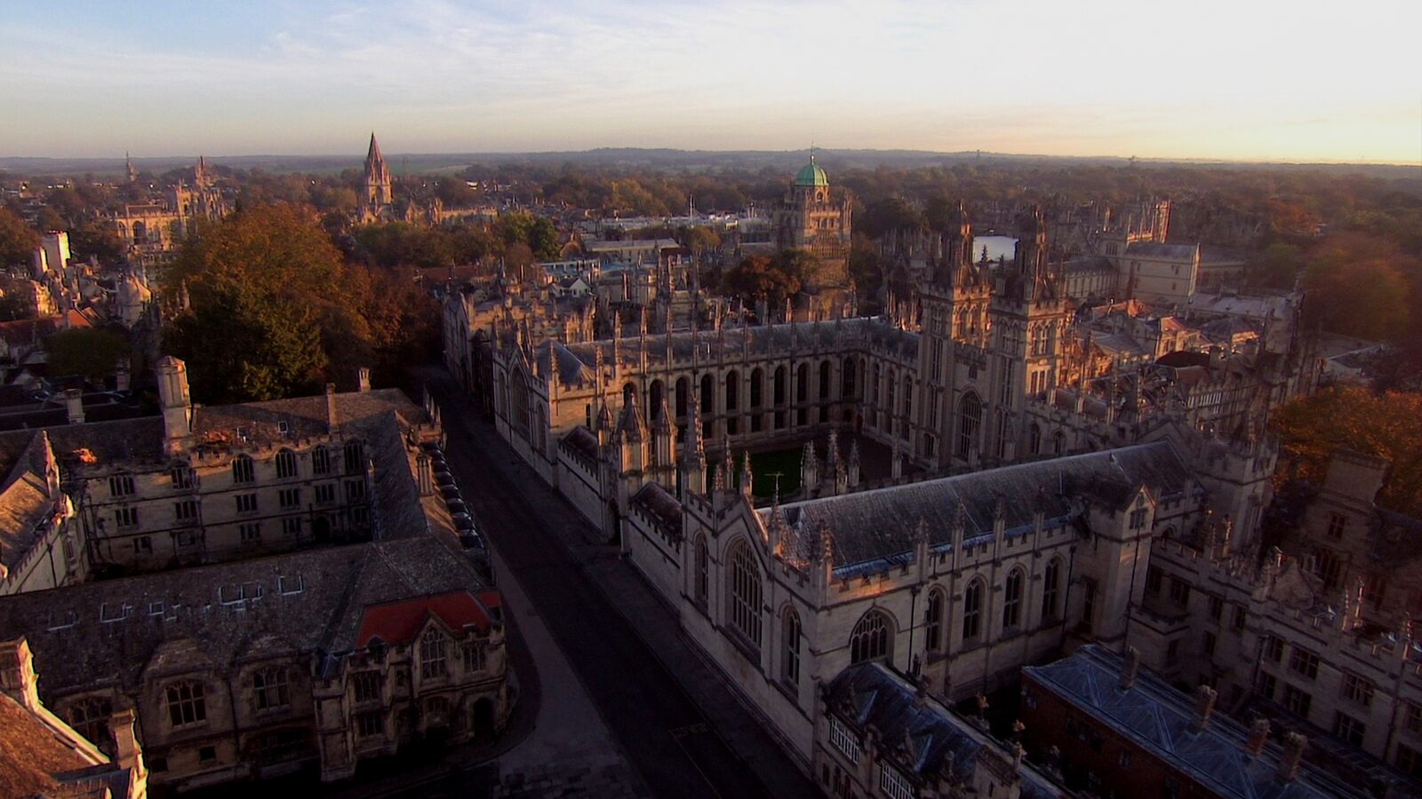 Golden morning light over the historic stone spires and quadrangles of Oxford under a soft autumn mist