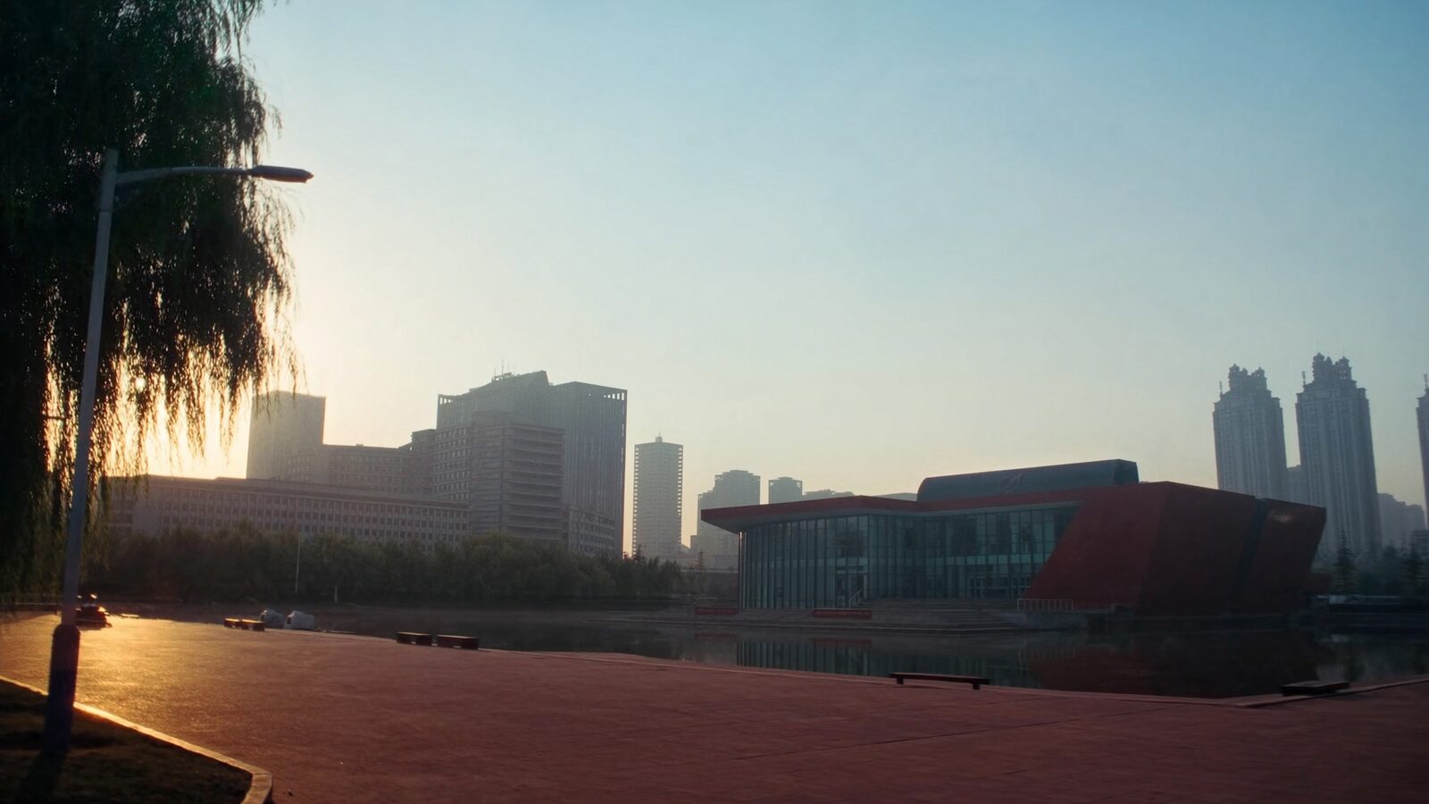 A quiet modern Chinese university campus at dawn with glass research buildings, a reflecting pond, and city towers in the misty distance