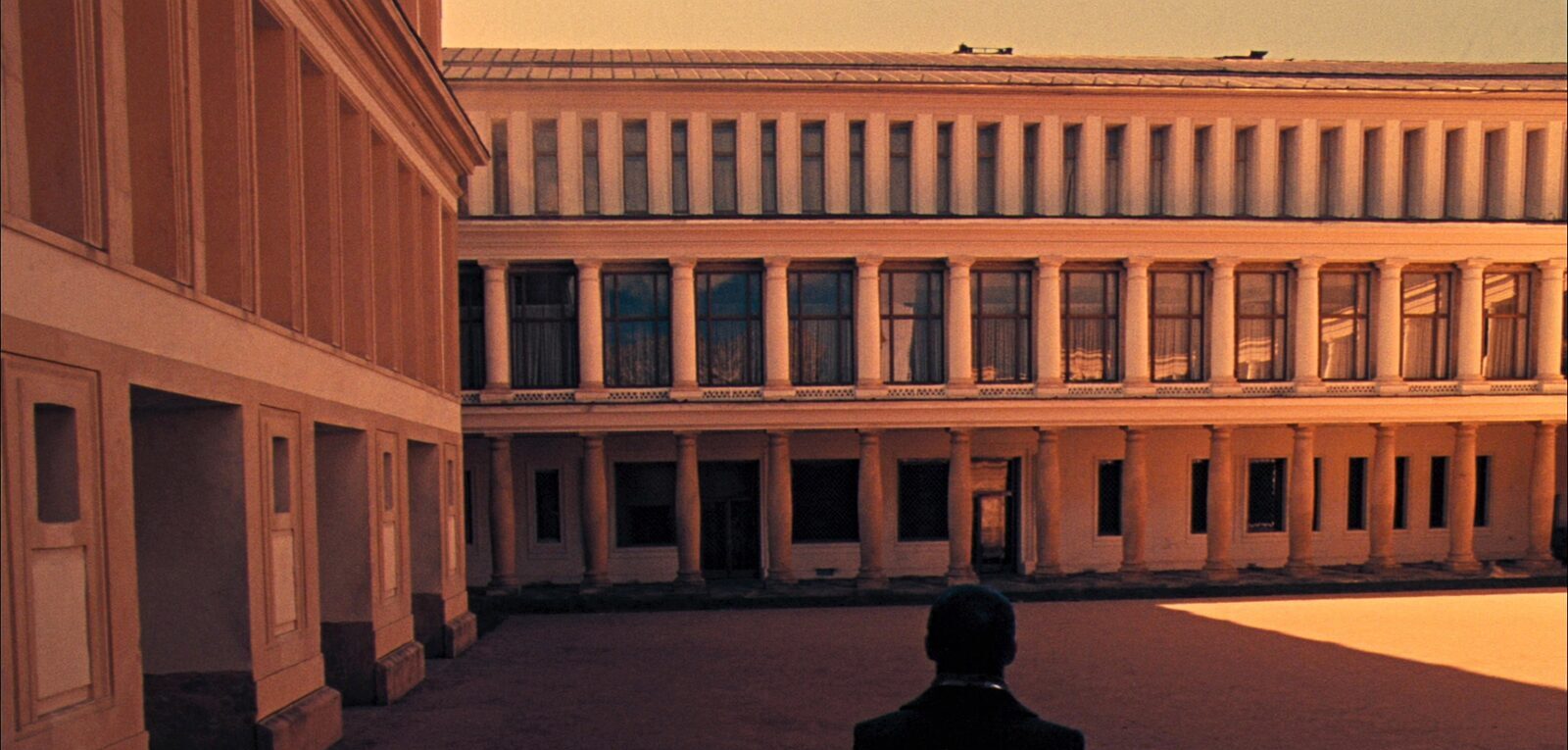 A grand German university building with a columned facade and courtyard at golden hour