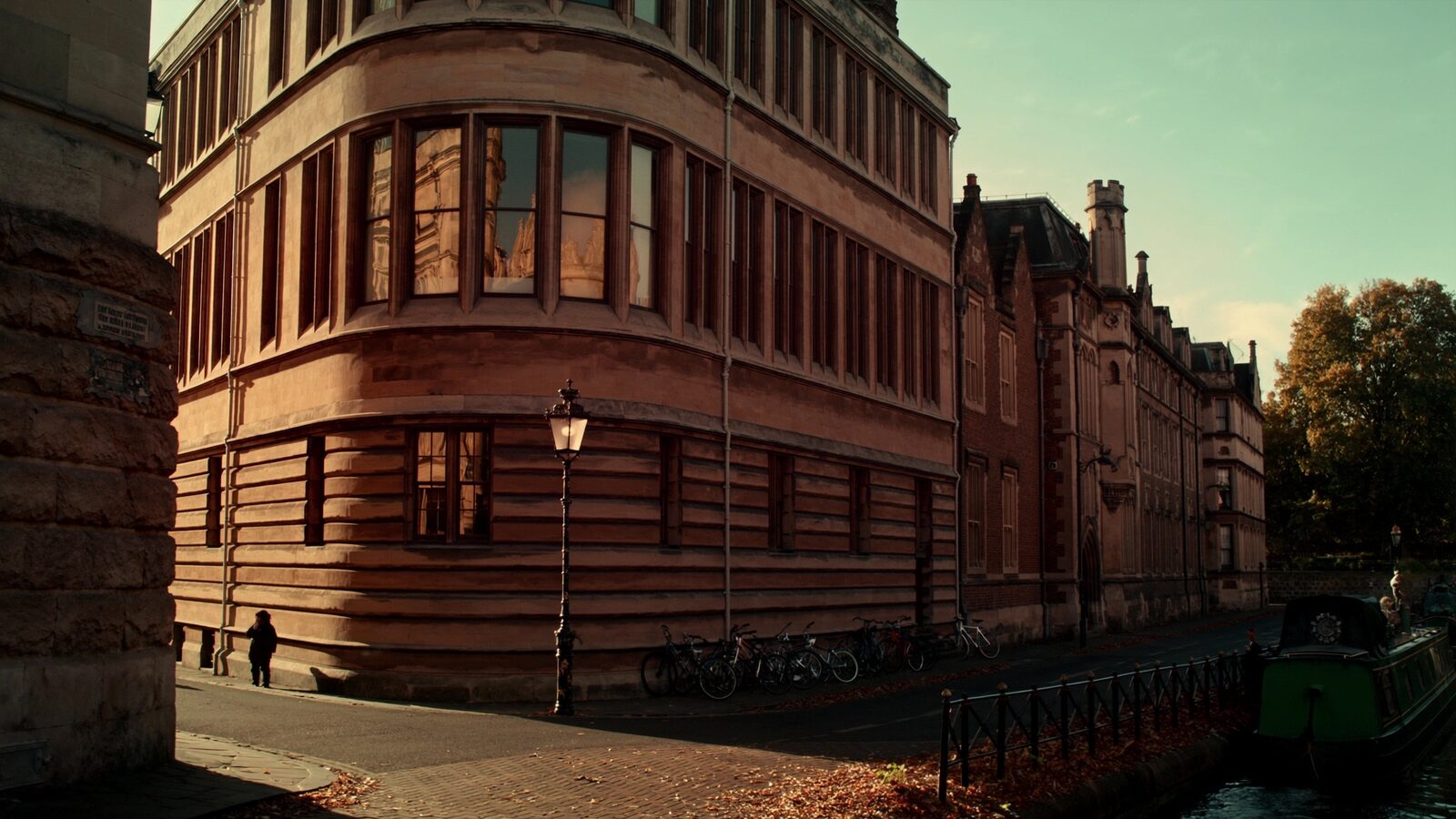 Golden-hour view of a canal-side European university quarter with historic science buildings and parked bicycles