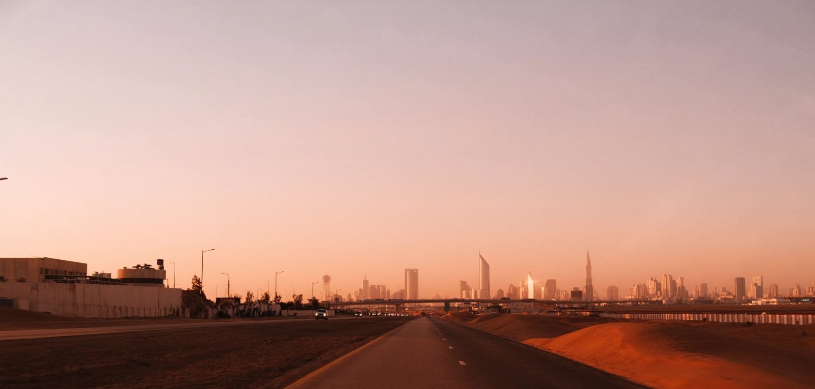 A long open highway stretching toward a distant city skyline at sunrise