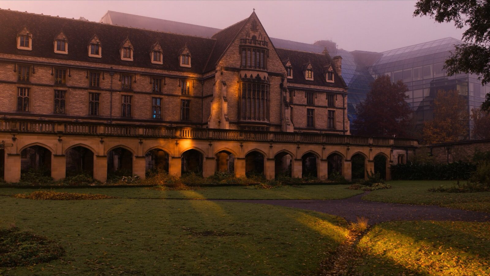 Empty historic European university courtyard at dawn with stone arcades and a modern research building behind