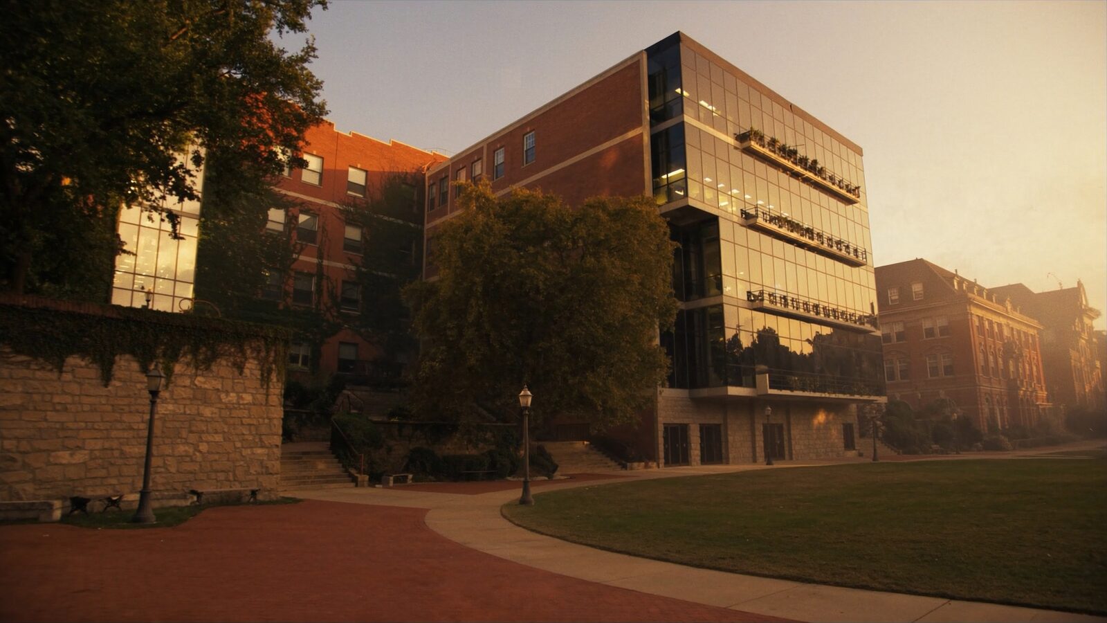 Empty university research quad at golden hour with brick buildings and a glass lab wing