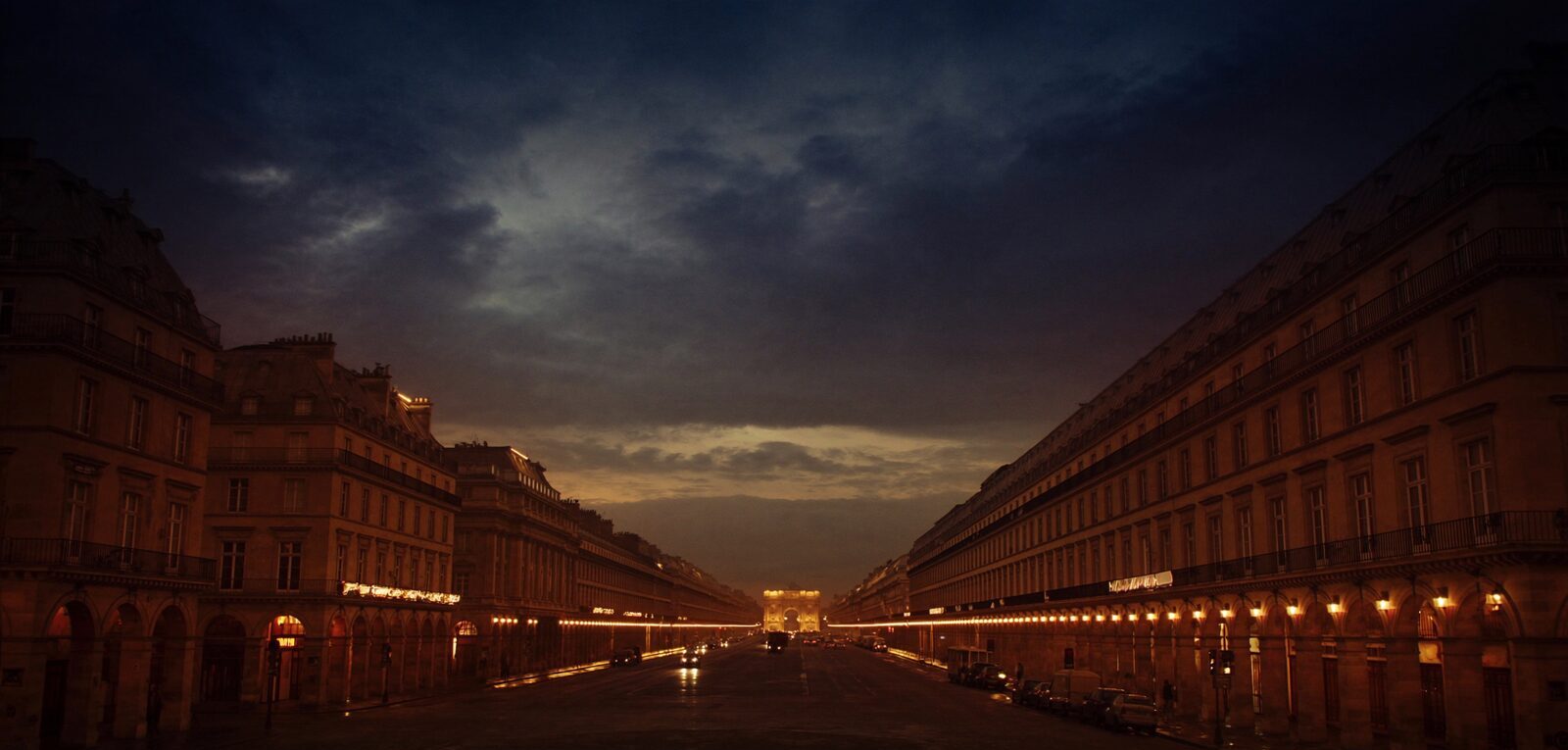 A Parisian boulevard of Haussmann architecture with warm street lamps at dusk