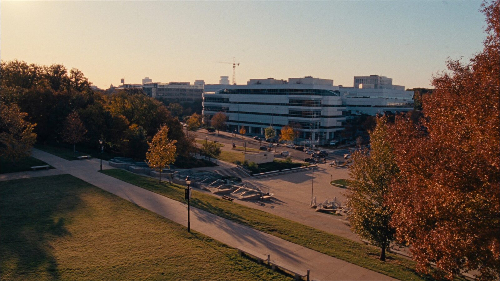 Empty university quad at golden hour with a modern glass campus in the distance