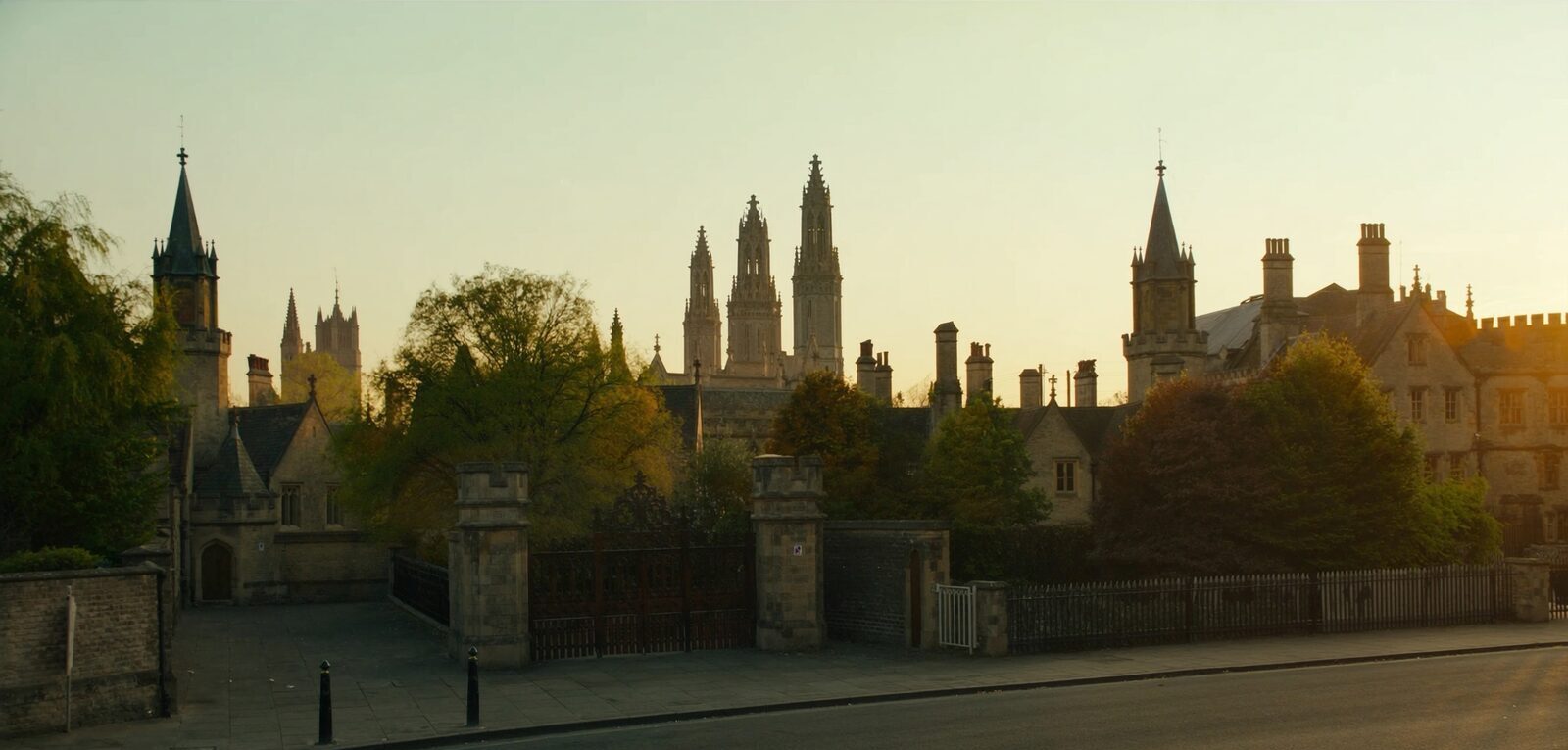 An Oxford-like university street of stone spires and college walls at golden hour